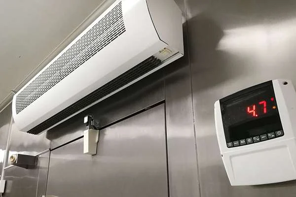 Ceiling-mounted air conditioner with a wall thermostat reading 4.7°C on a stainless steel wall.